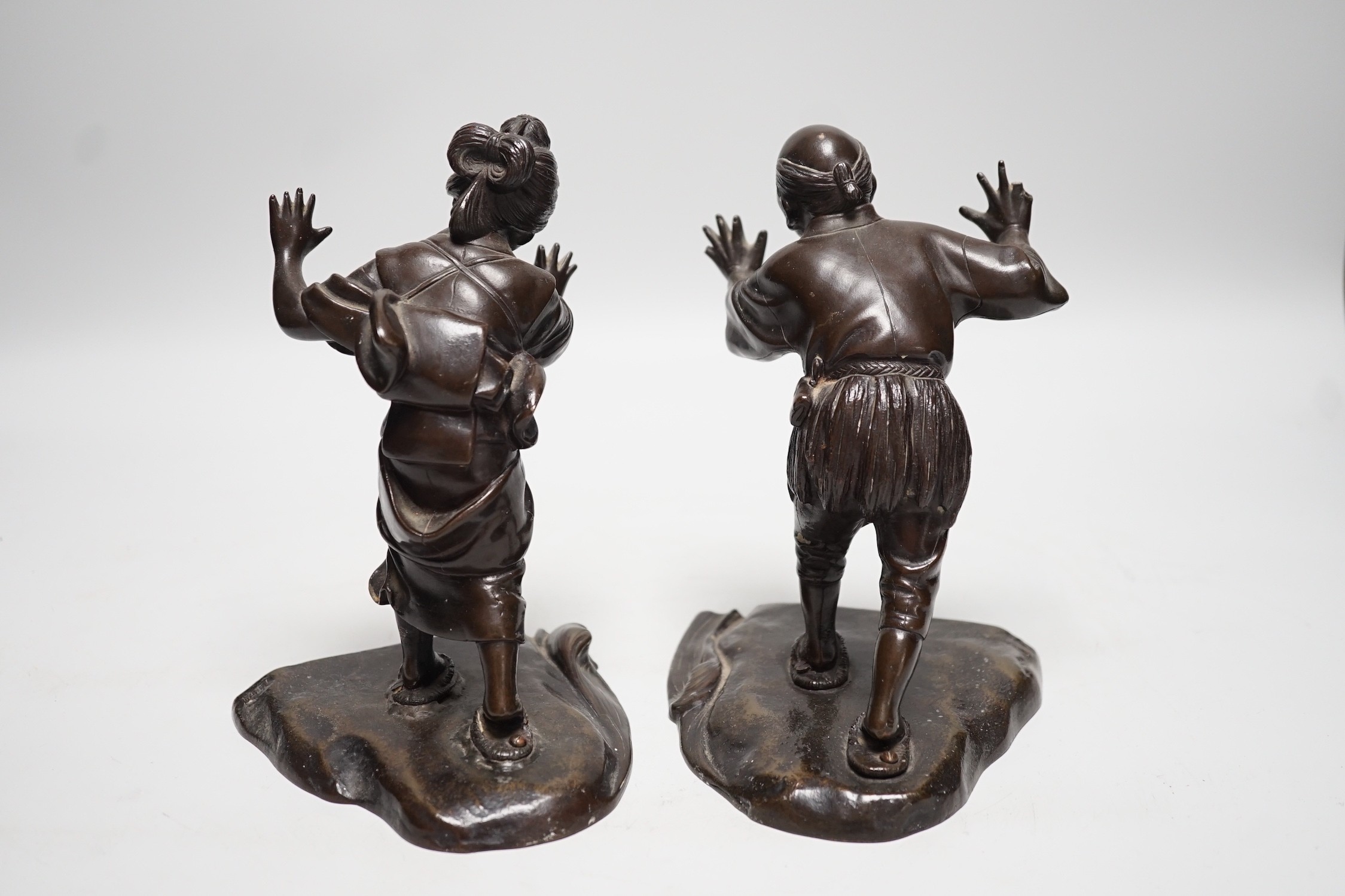 A pair of Japanese Meiji period bronze bookends modelled as a husband and wife pushing against each other, 18cm